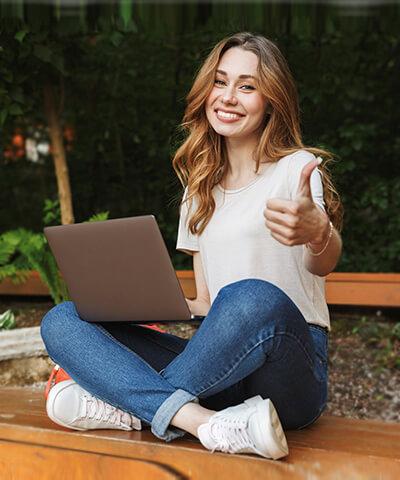 Ventajas para particulares - Joven chica sonriendo sentada utilizando un portátil