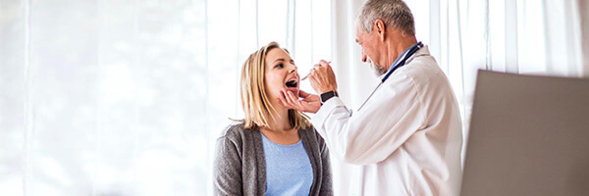Seguro de Salud - Doctor senior examinando a una joven mujer en su consulta médica Seguro de Salud - Doctor senior examinando a una joven mujer en su consulta médica
