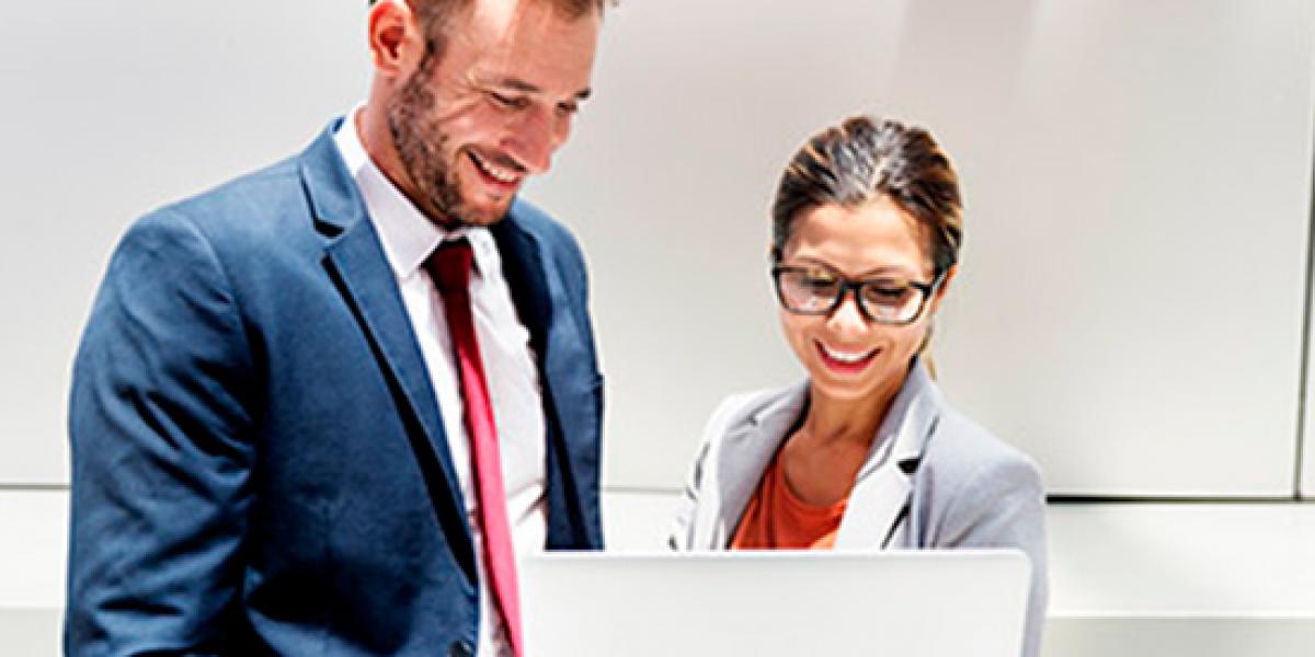 Financiación de impuestos-Dos empleados comparten impresiones delante de un portatil Financiación de impuestos-Dos empleados comparten impresiones delante de un portatil